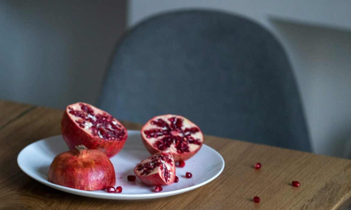 pomegranate fruit sliced into half on white plate